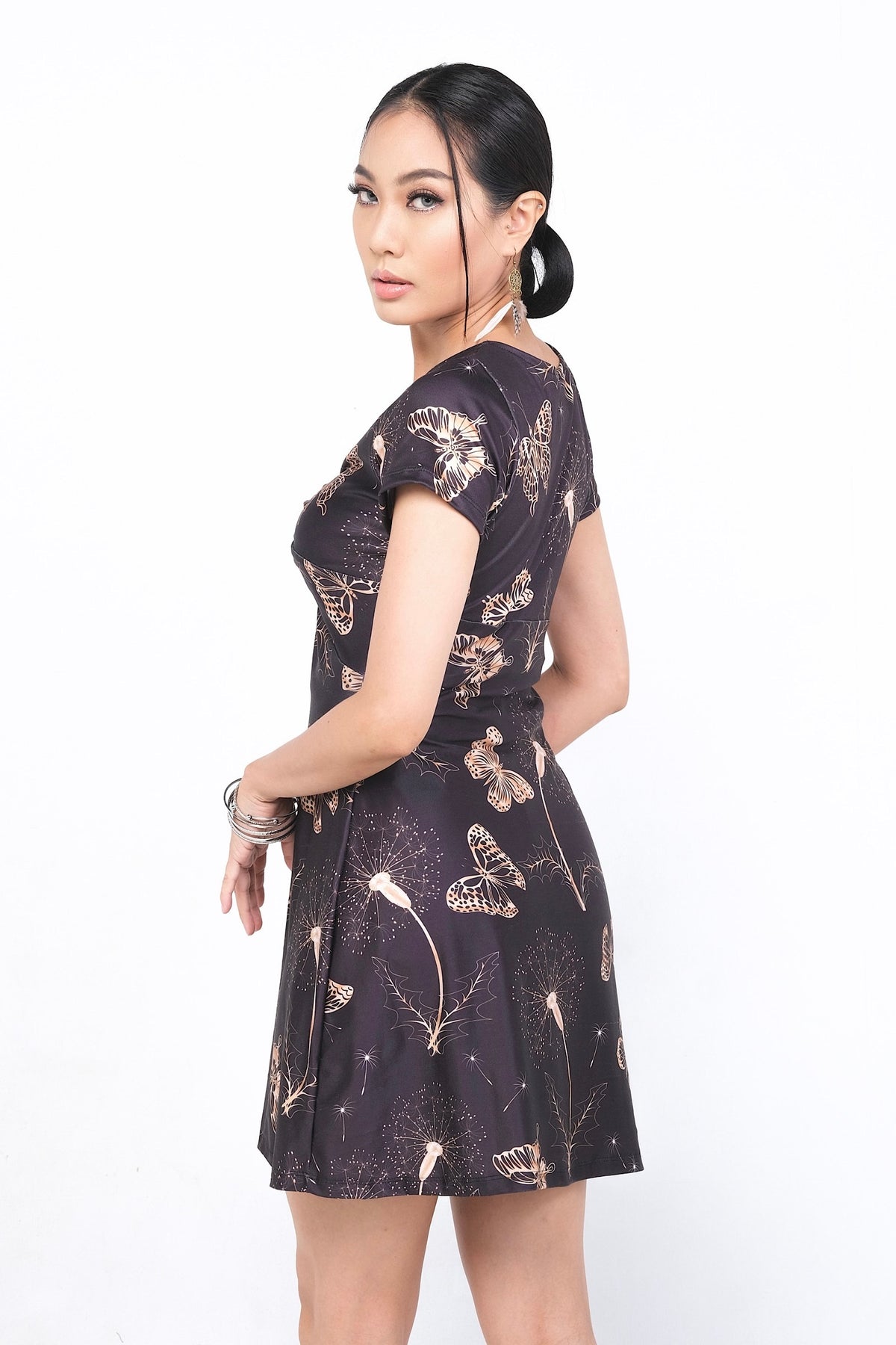 Robe Nolana en polyester et spandex, avec un motif délicat de papillons et de plantes sur fond noir, idéale pour une tenue printanière ou estivale élégante. Disponible sur Trop Belle Pour Toi.