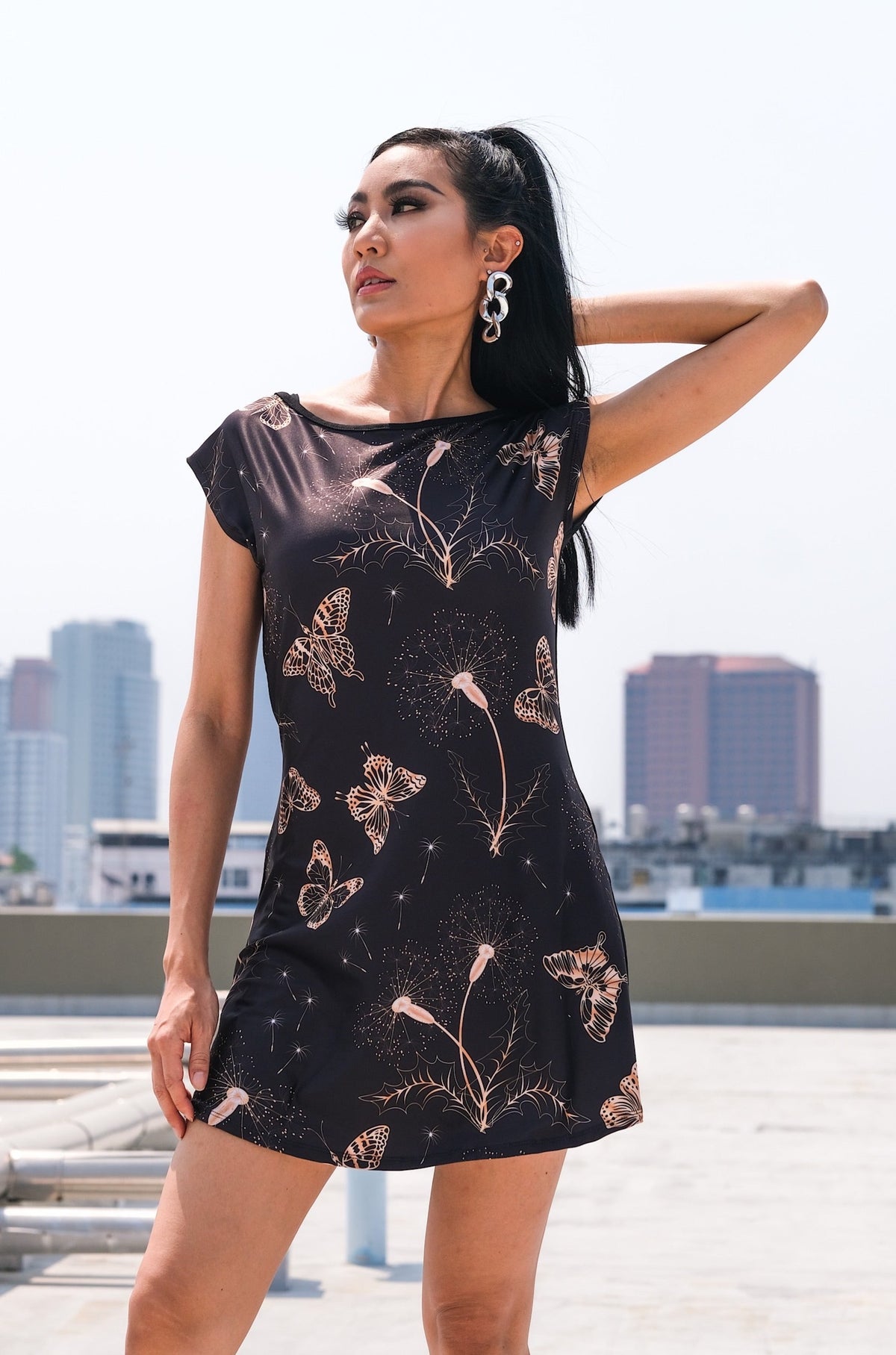 Tunique Cora avec un motif de papillons et de dandelions, conçue en polyester pour l'avant et spandex pour l'arrière. Parfaite pour toute silhouette