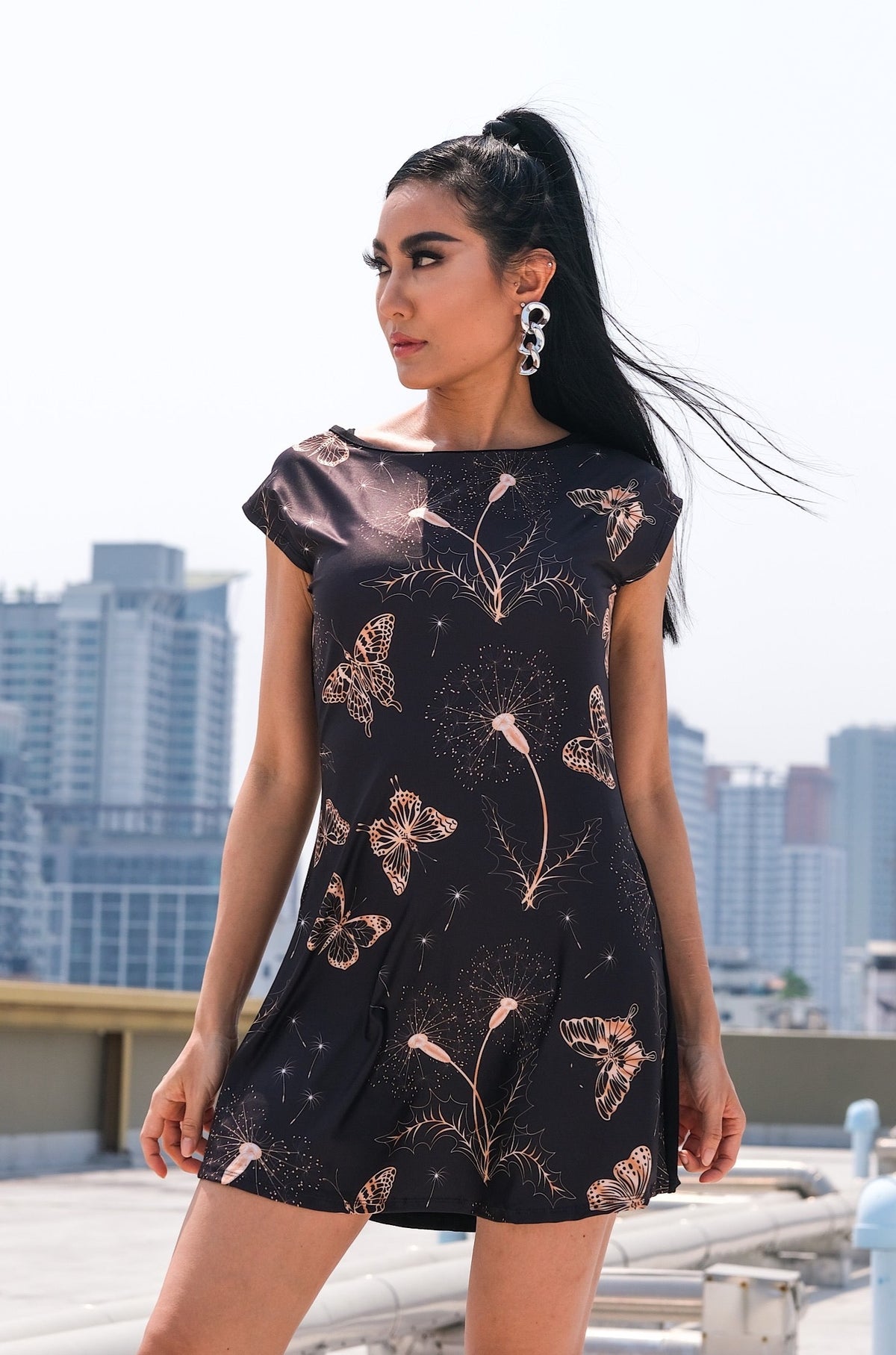 Tunique Cora avec un motif de papillons et de dandelions, conçue en polyester pour l'avant et spandex pour l'arrière. Parfaite pour toute silhouette